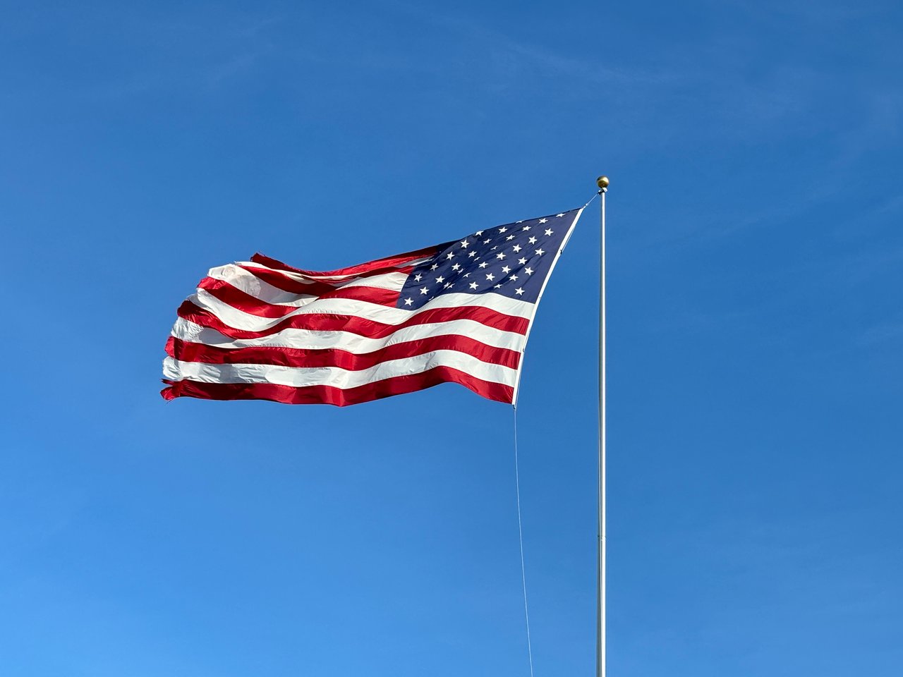 American flag blowing in the blue sky