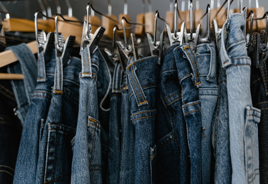 Jeans in multiple different washes hanging on a rack.