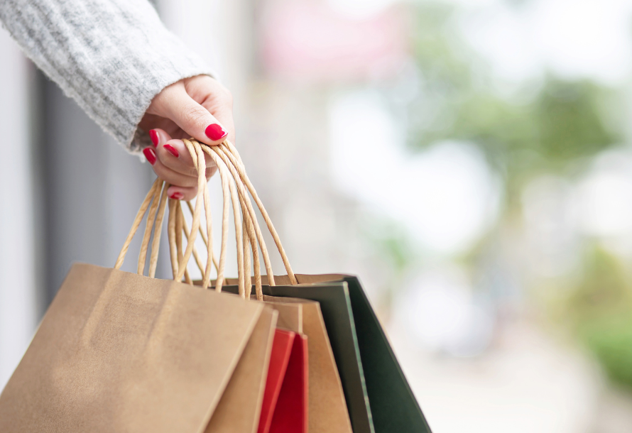 A person with painted nails holding several shopping bags.