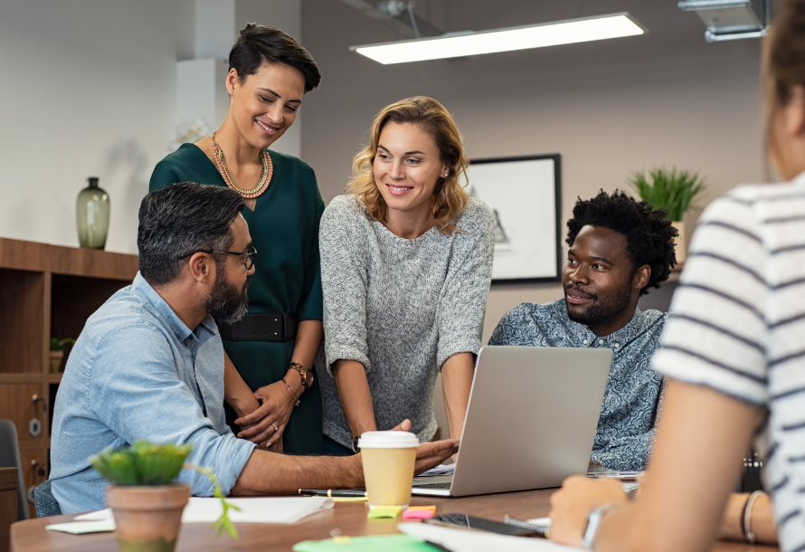 A group of people working together in front of a laptop.