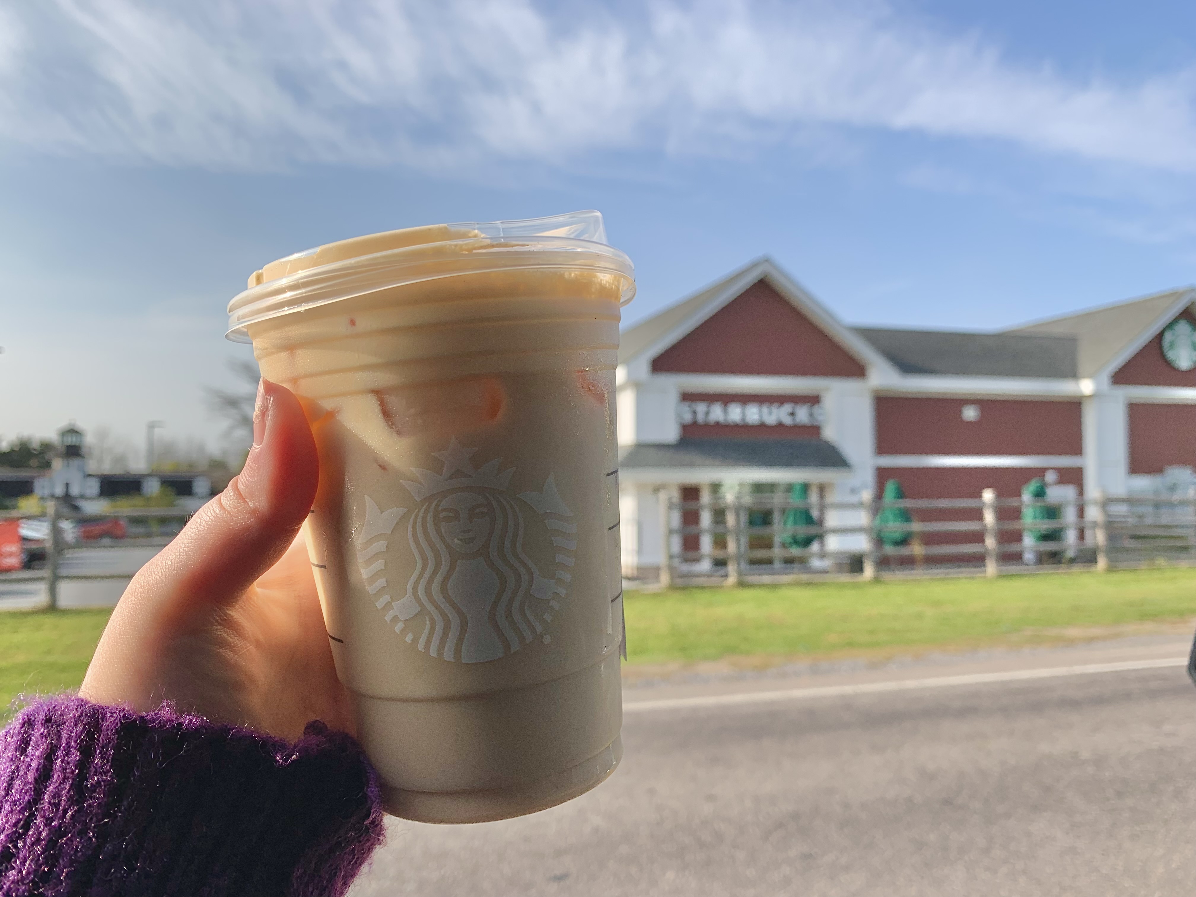 Pumpkin Spice Latte in front of Starbucks building.