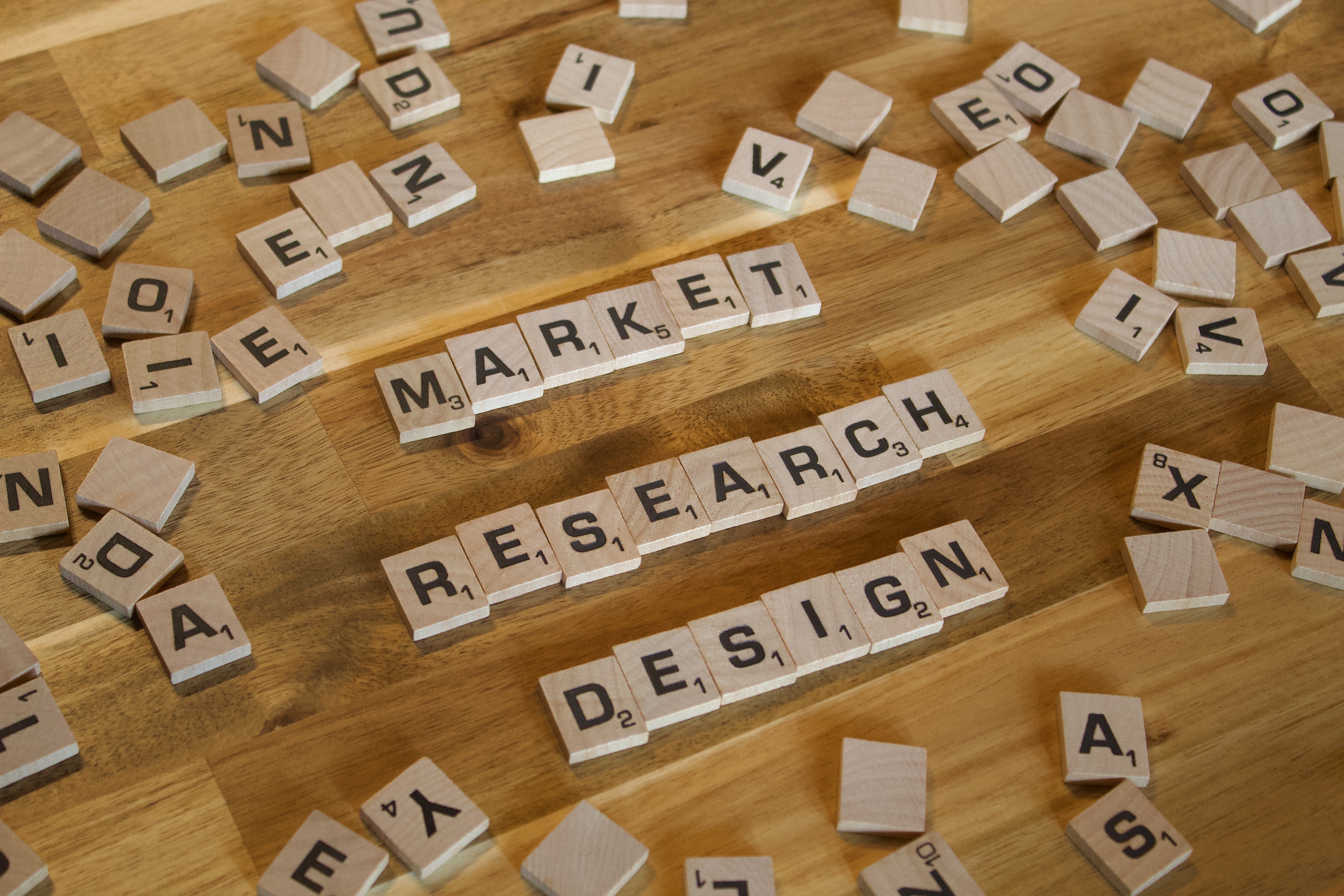 Market, research, design spelled out in Scrabble letters on a wooden table.