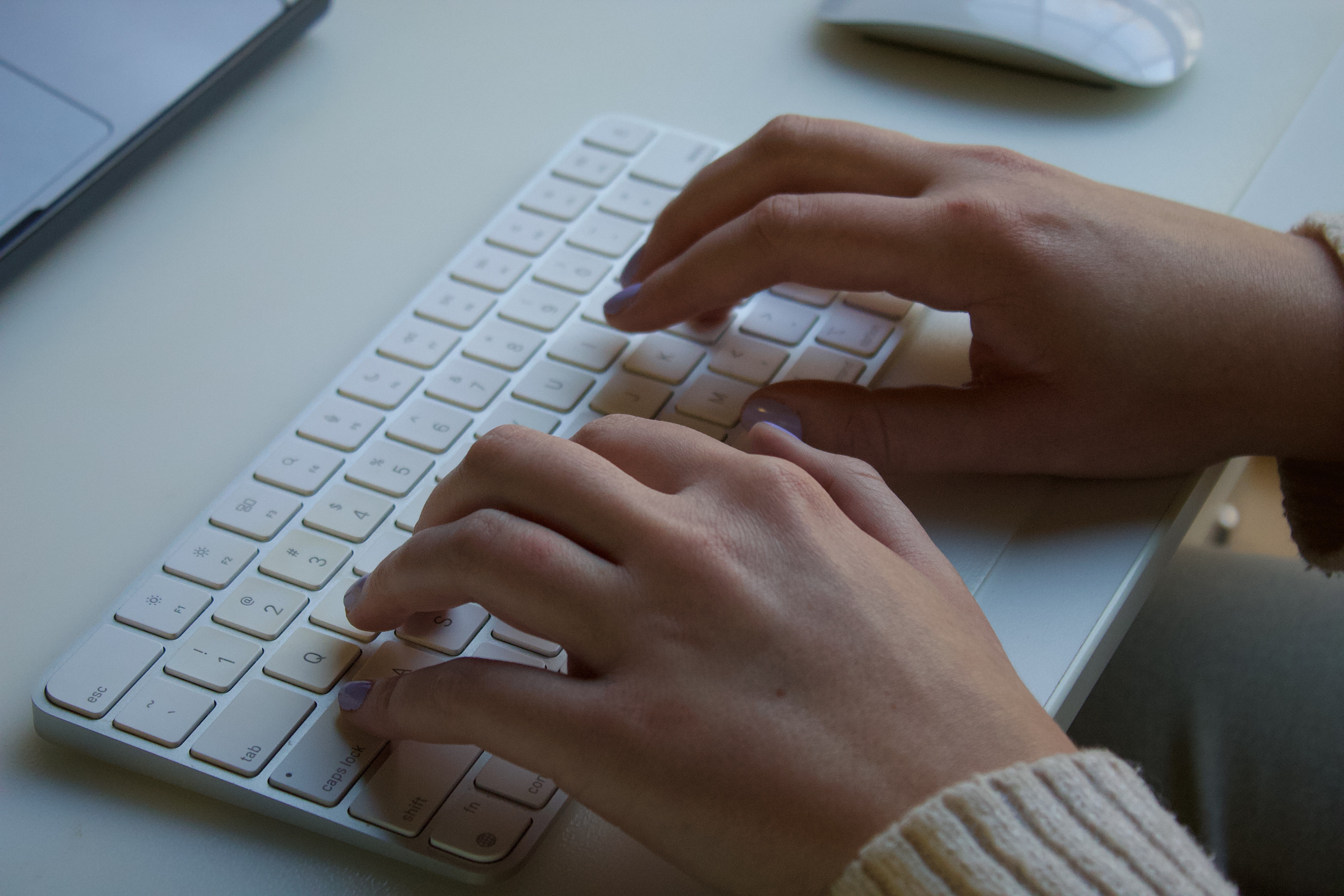 Fingers typing on a Mac keyboard
