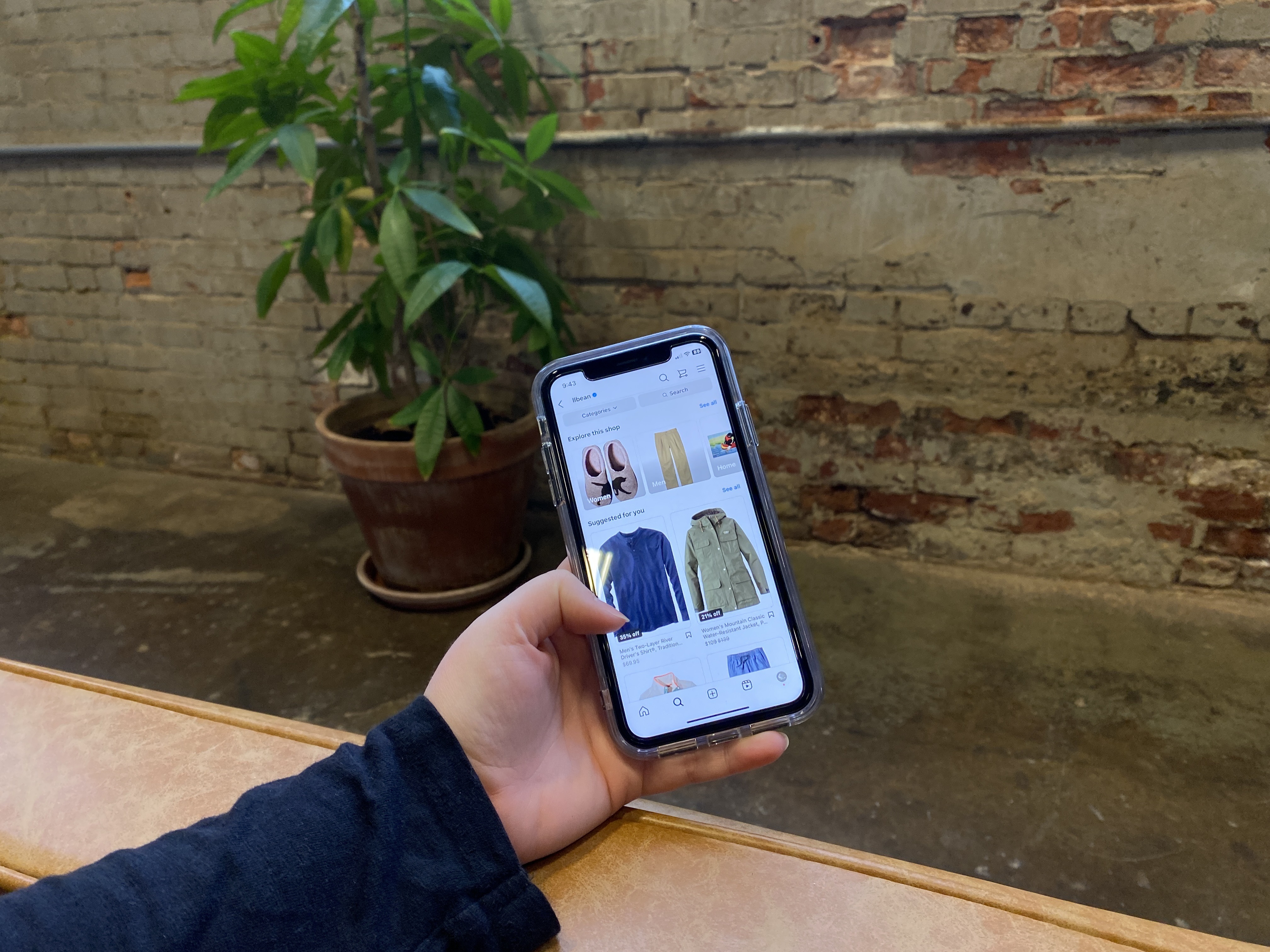 Instagram shop open on an iPhone, in front of a leafy plant and a brick wall.
