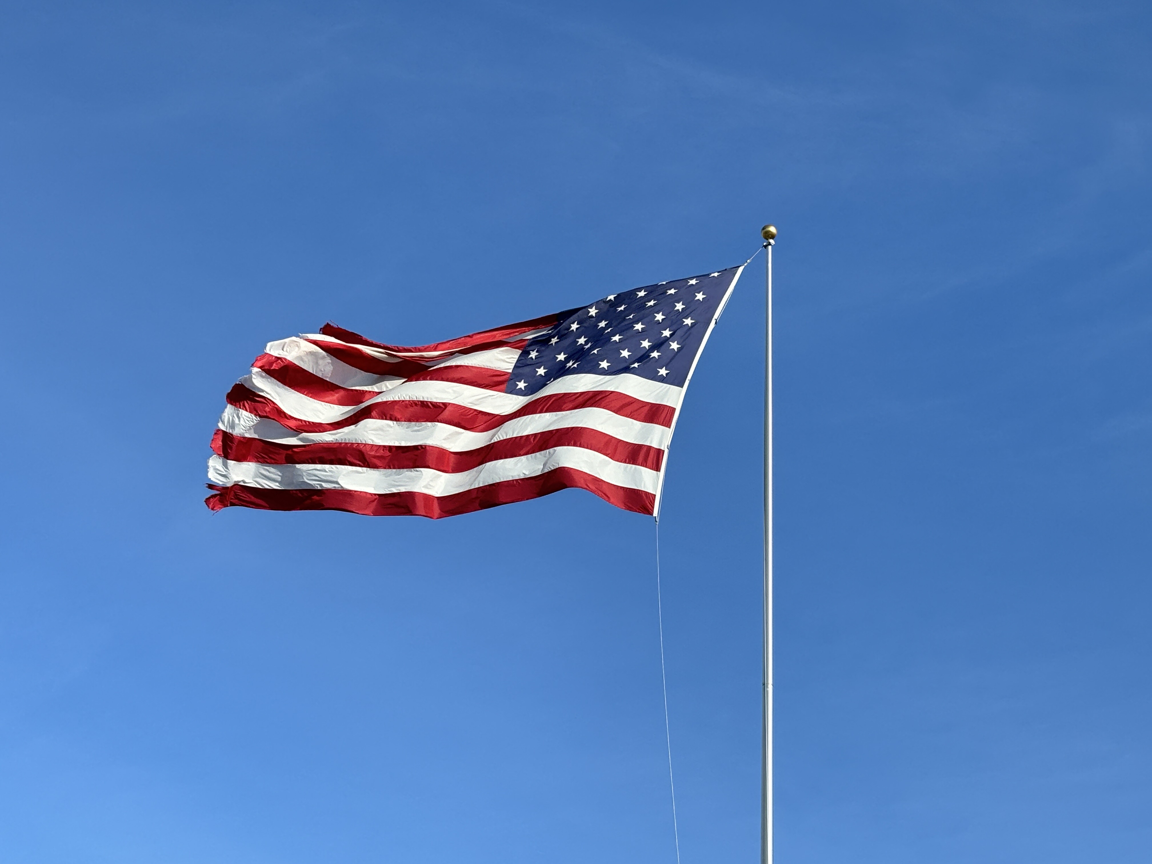 American flag blowing in the blue sky