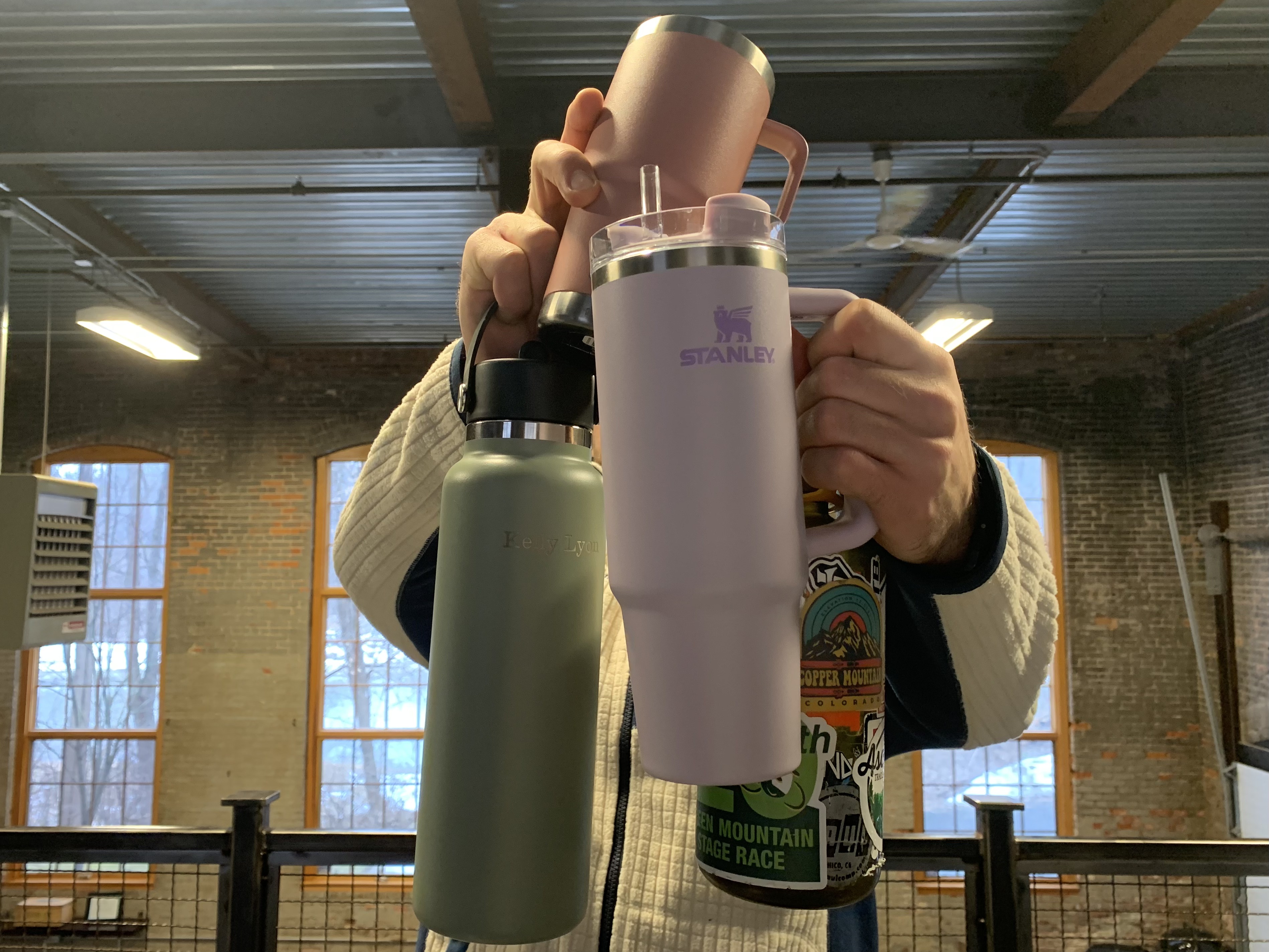 Cooper holding a Stanley, Hydro Flask, Yeti, and Nalgene water bottle.