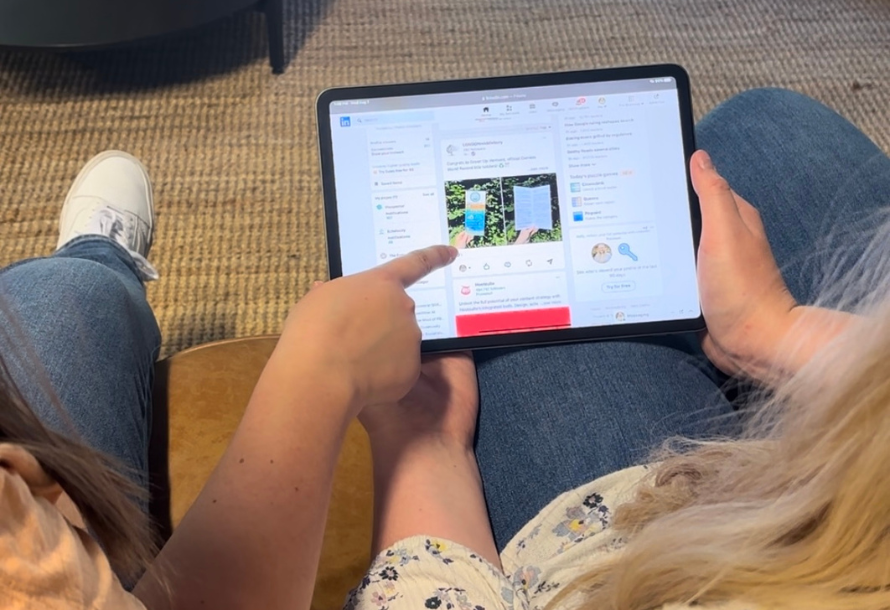 One person pointing at a LinkedIn feed on another person's iPad.