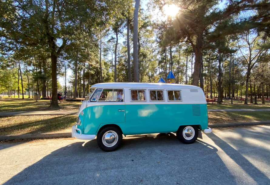 Light blue Volkswagen bus driving down the road.