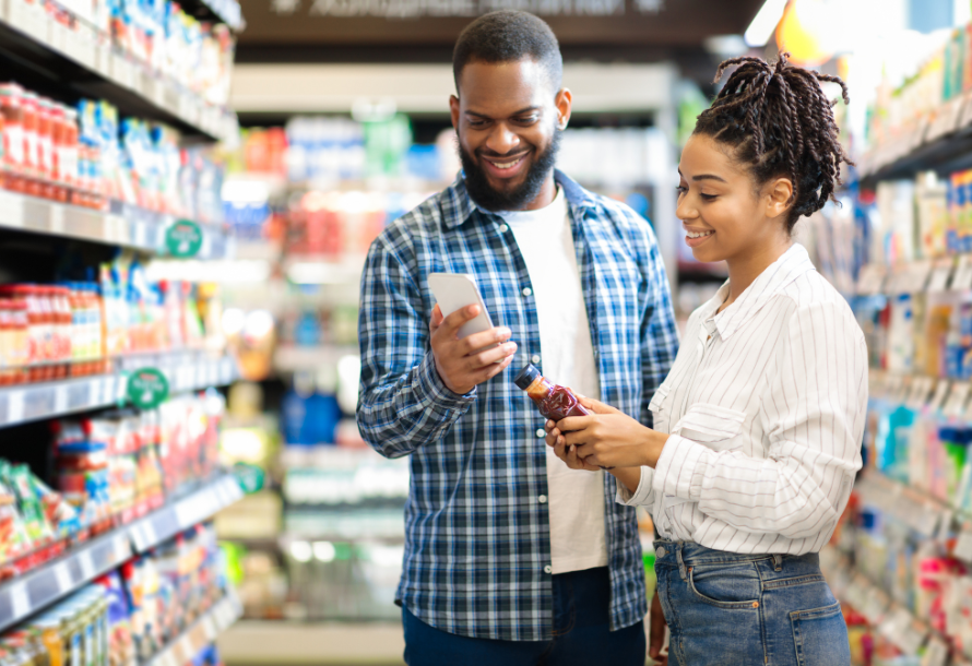 A man and a woman look at a product in the grocery aisle.