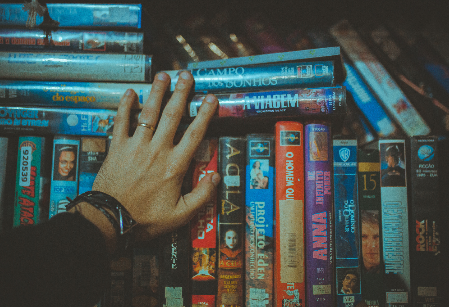 Person's hand looking at VHS tapes.